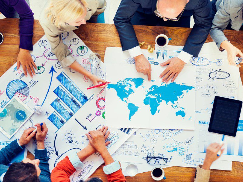 A group of people sitting around a table with papers on it.