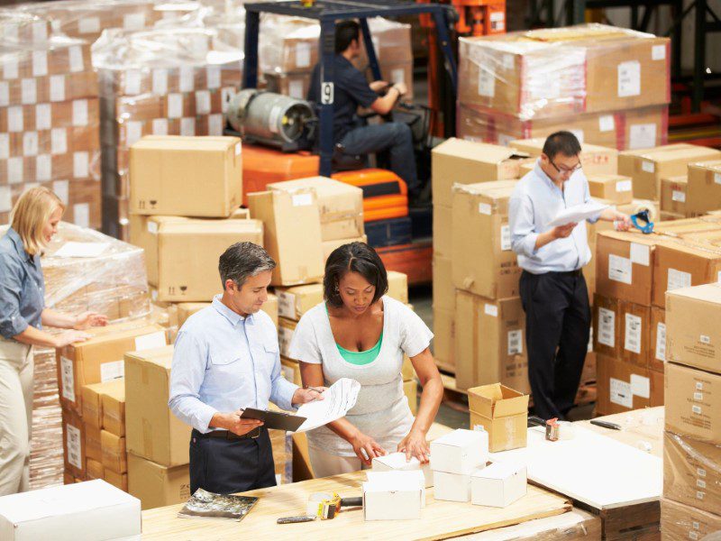 A group of people in warehouse with boxes.