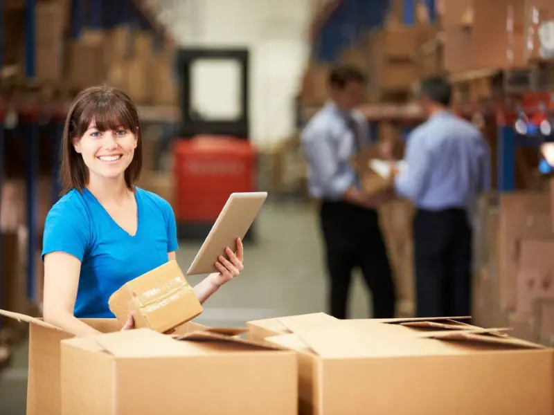 A woman holding an ipad in front of boxes.