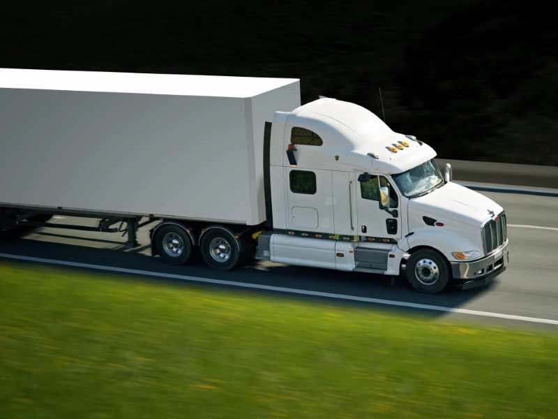 A white truck is driving down the road.