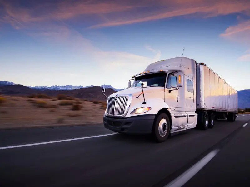 A white semi truck driving down the road.