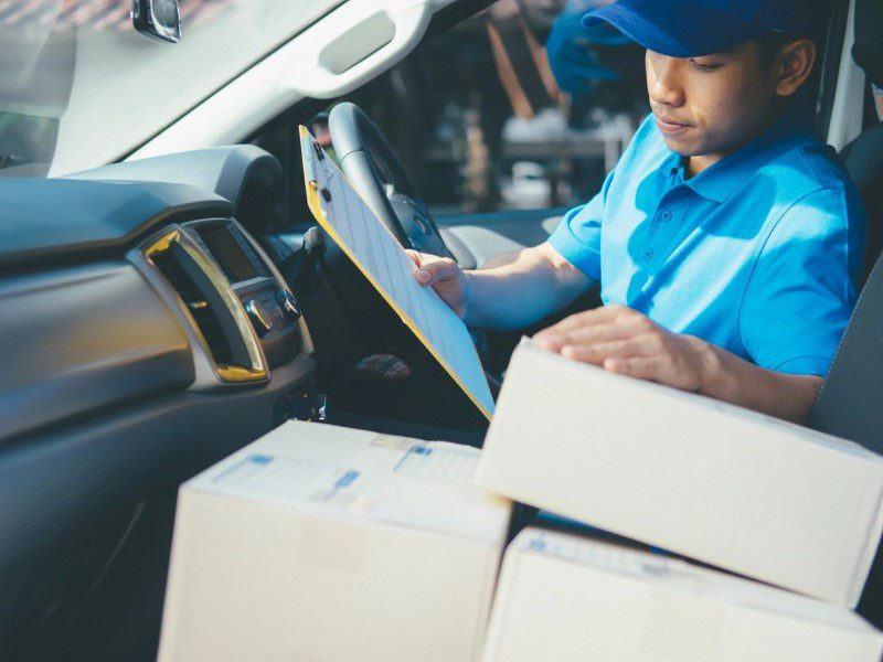 A man in blue shirt holding clipboard near boxes.