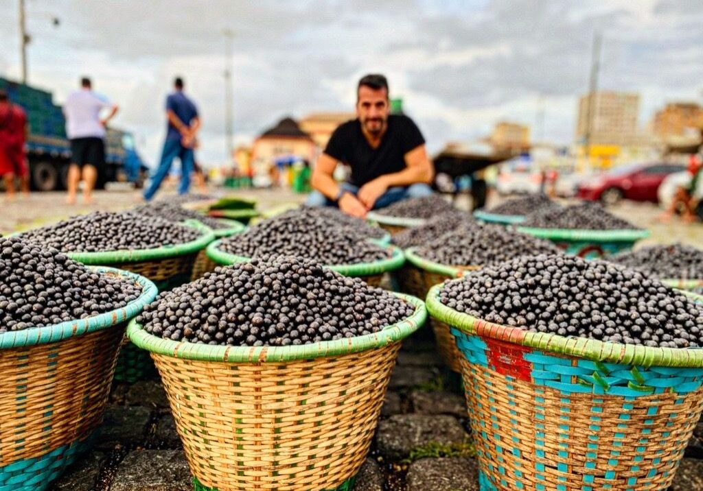 A man sitting in front of baskets filled with black olives.