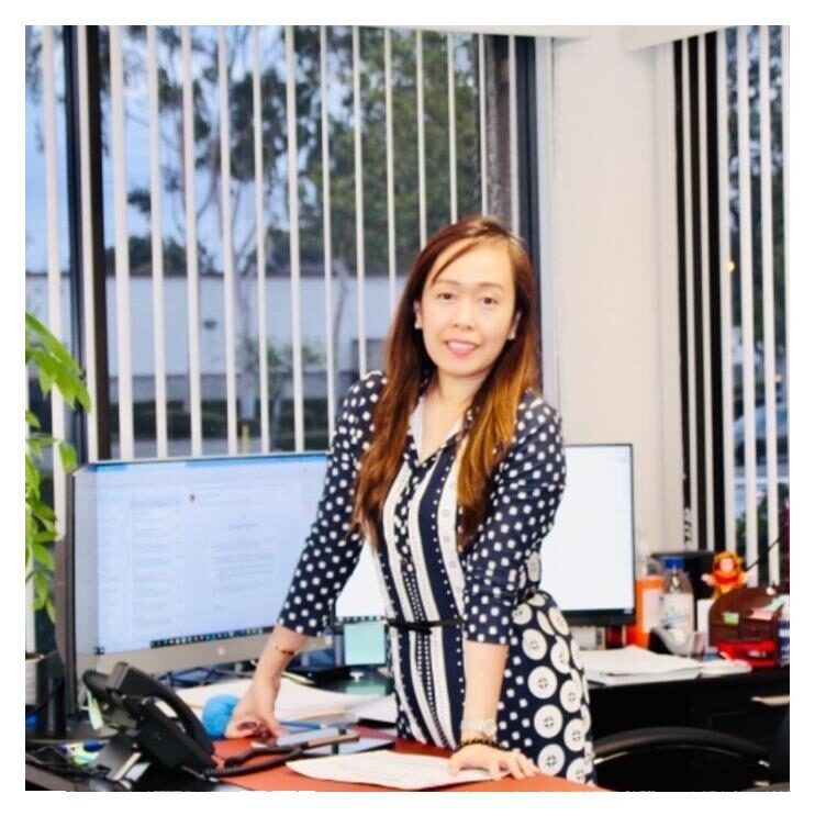 A woman standing in front of a desk.